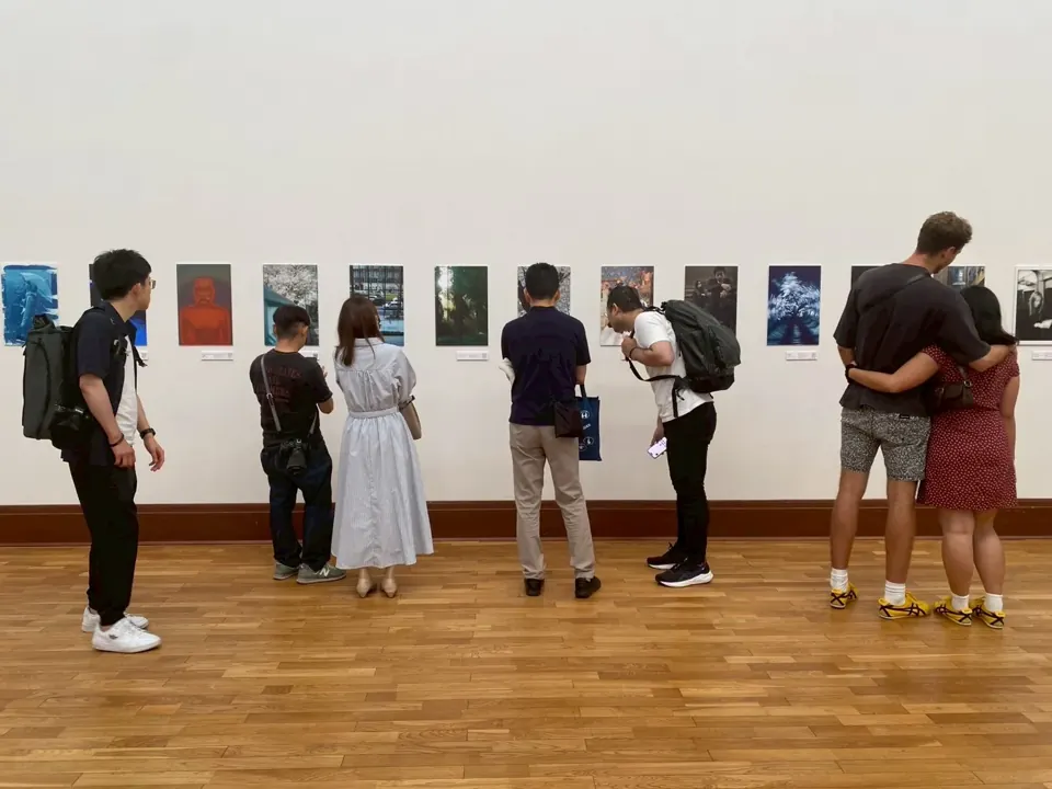 壁に並んだ写真作品を鑑賞する来場者（京都市京セラ美術館 ECHO）