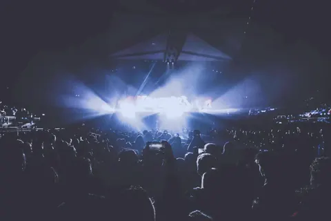 照明に照らされたライブ会場で、観客がスマートフォンで撮影している