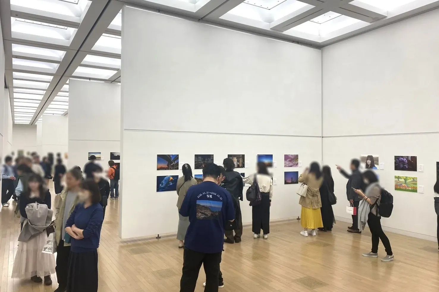 国立新美術館で開催した写展の展示風景。白い壁に写真パネルが並び、来場者が見て回っている